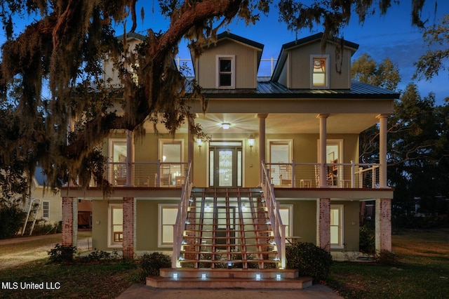 view of front facade with a ceiling fan, metal roof, covered porch, stairs, and stucco siding