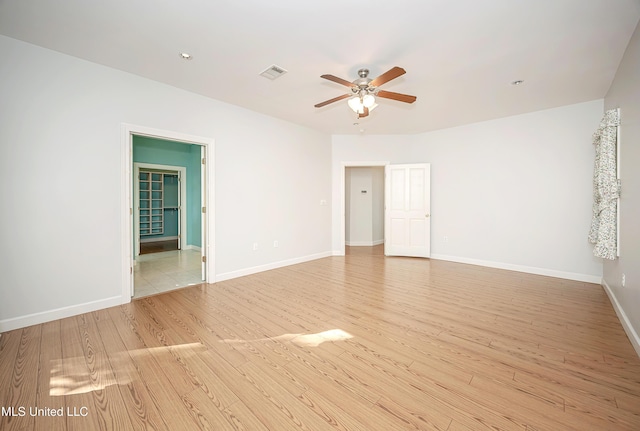 empty room featuring baseboards, ceiling fan, visible vents, and light wood-style floors