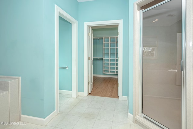 corridor with light tile patterned flooring, visible vents, and baseboards