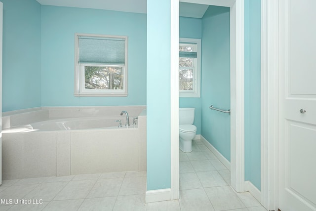 bathroom with toilet, tile patterned flooring, a bath, and baseboards