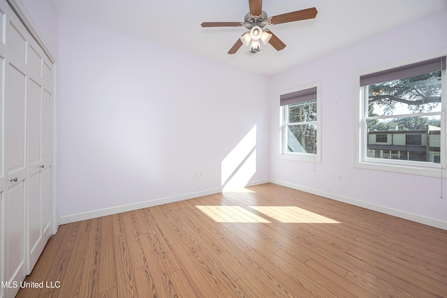 empty room with baseboards, a ceiling fan, and light wood-style floors