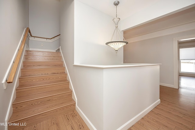 staircase featuring wood finished floors and baseboards