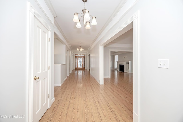 hallway with baseboards, light wood-style flooring, a chandelier, and crown molding