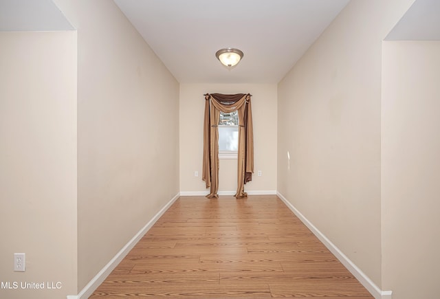 unfurnished room featuring baseboards and light wood finished floors