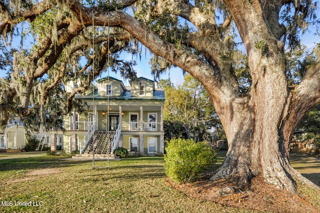 view of front facade featuring covered porch, stairs, metal roof, and a front yard