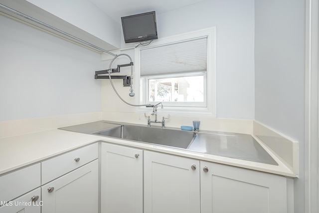 kitchen with white cabinets, open shelves, light countertops, and a sink