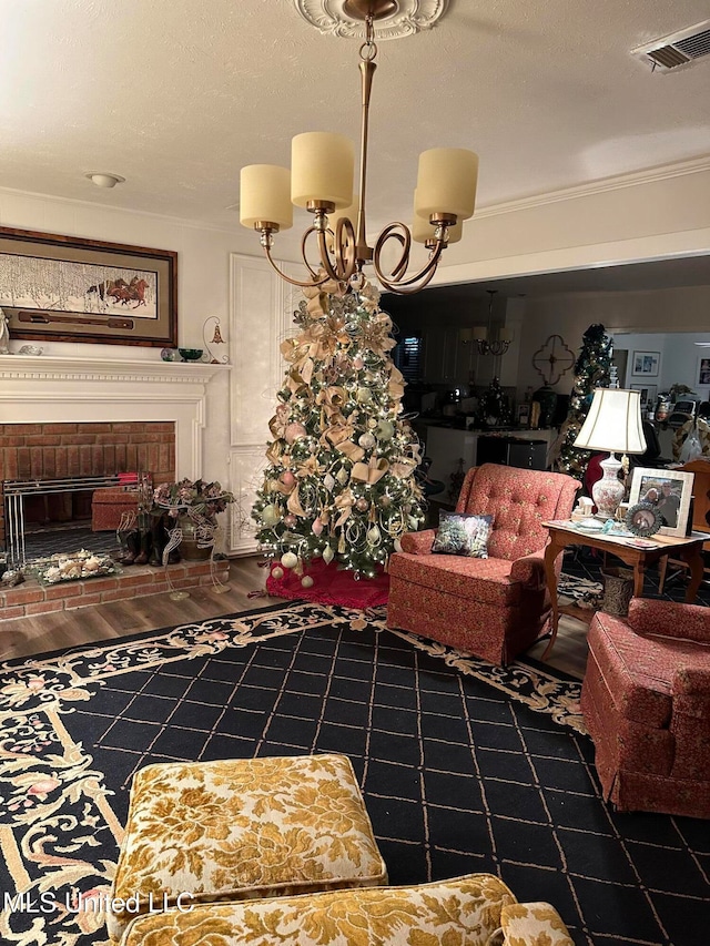 living room with crown molding, a fireplace, visible vents, wood finished floors, and a chandelier