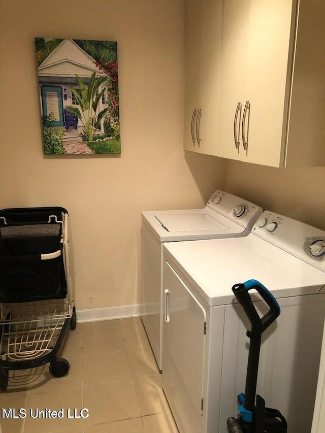 laundry area with light tile patterned floors, washer and clothes dryer, baseboards, and cabinet space