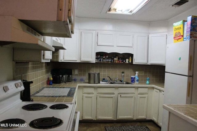 kitchen featuring white appliances, sink, backsplash, white cabinetry, and tile counters