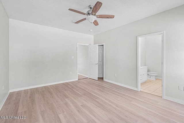 unfurnished bedroom with ensuite bathroom, light hardwood / wood-style flooring, ceiling fan, and a textured ceiling