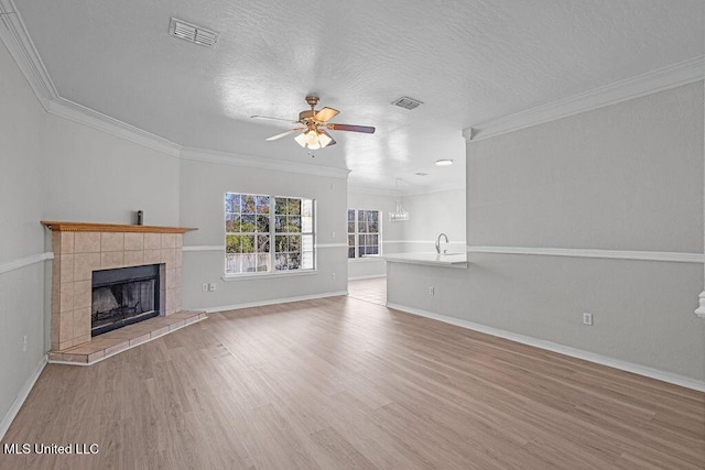 unfurnished living room featuring a fireplace, light hardwood / wood-style flooring, ceiling fan, and ornamental molding