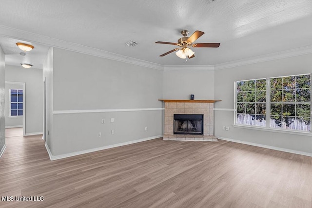 unfurnished living room with ceiling fan, crown molding, a tile fireplace, and light hardwood / wood-style flooring