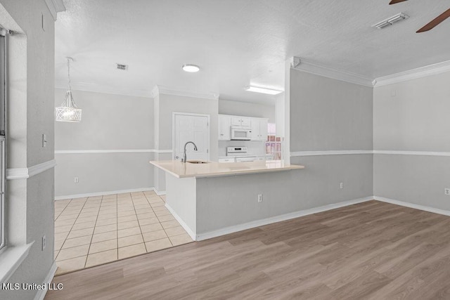 kitchen with white appliances, white cabinets, sink, light hardwood / wood-style flooring, and kitchen peninsula