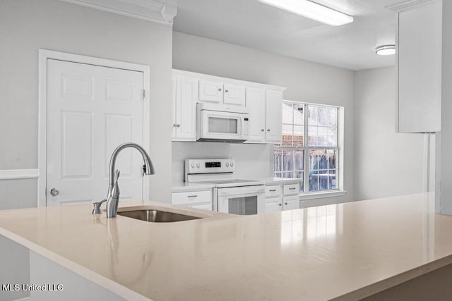 kitchen with kitchen peninsula, sink, white cabinets, and white appliances