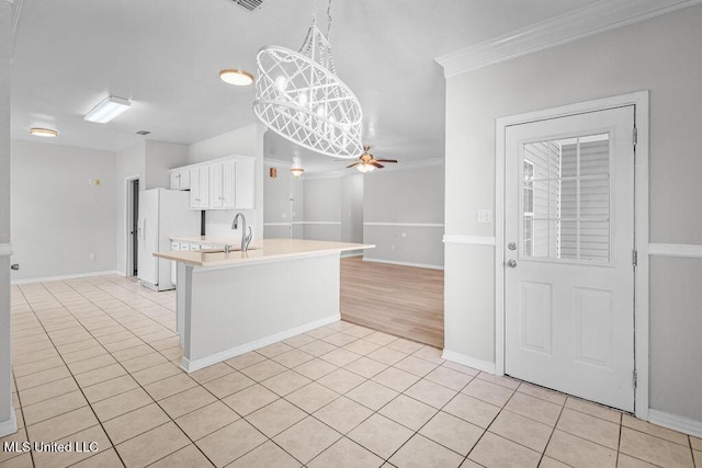 kitchen featuring pendant lighting, white refrigerator with ice dispenser, crown molding, ceiling fan, and light tile patterned floors