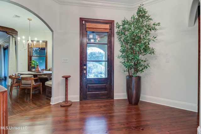 foyer entrance featuring wood finished floors, visible vents, an inviting chandelier, arched walkways, and ornamental molding