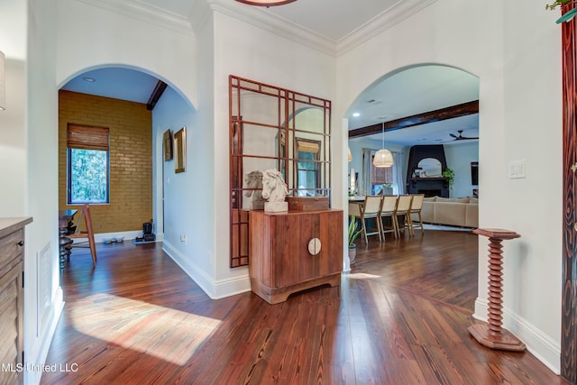 hallway with arched walkways, ornamental molding, brick wall, and wood-type flooring