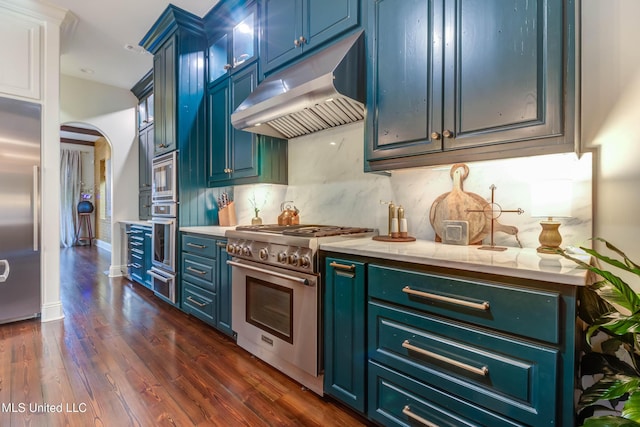 kitchen featuring a warming drawer, under cabinet range hood, arched walkways, decorative backsplash, and built in appliances