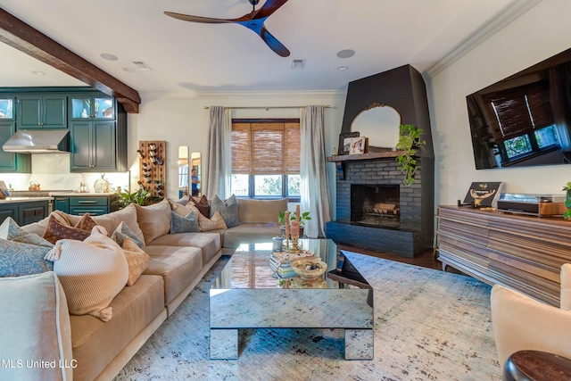 living area with visible vents, crown molding, a fireplace, wood finished floors, and a ceiling fan