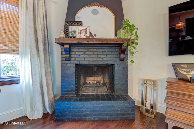 interior details featuring a brick fireplace, wood finished floors, and baseboards