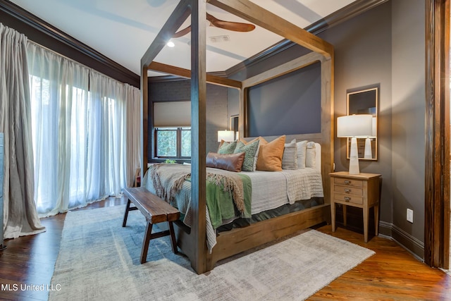 bedroom with visible vents, baseboards, wood finished floors, and ornamental molding