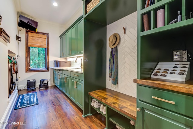 kitchen featuring a sink, crown molding, butcher block counters, green cabinetry, and decorative backsplash