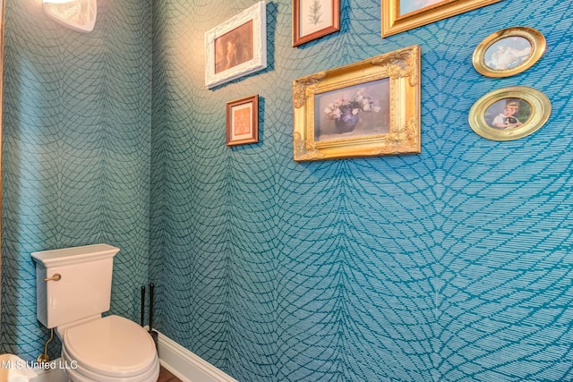 bathroom featuring wallpapered walls, toilet, and baseboards