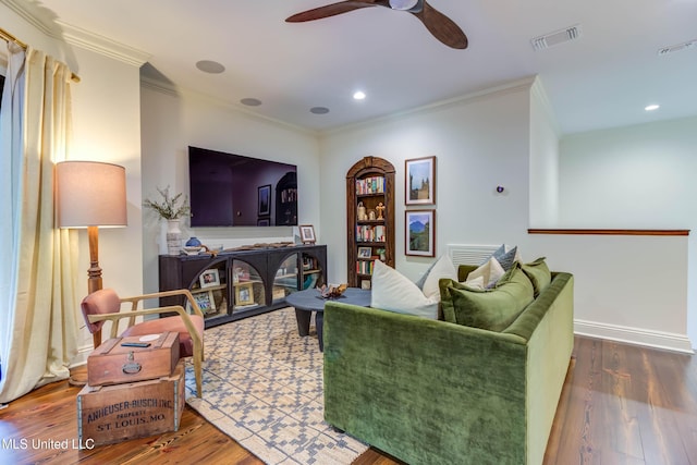 living area featuring visible vents, wood finished floors, a ceiling fan, and ornamental molding