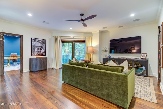 living area with visible vents, ornamental molding, ceiling fan, and wood finished floors