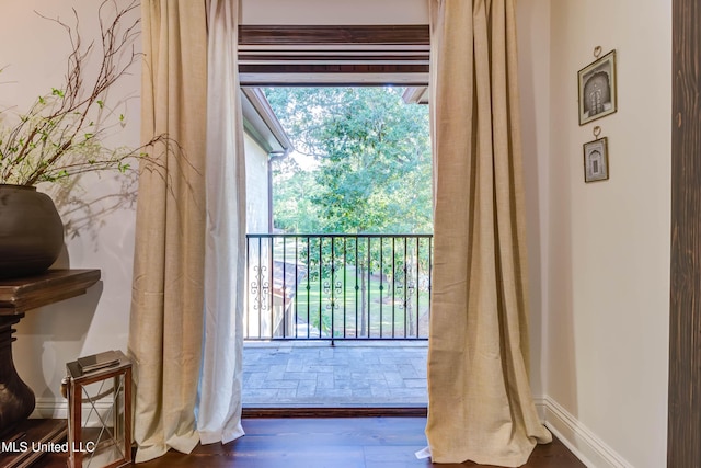 doorway to outside featuring plenty of natural light, wood finished floors, and baseboards