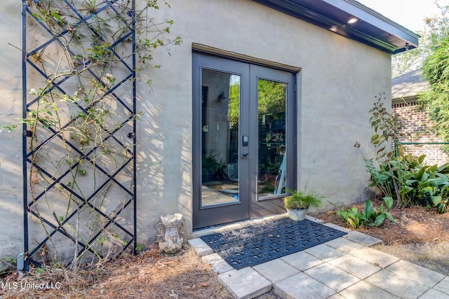 entrance to property featuring stucco siding and french doors