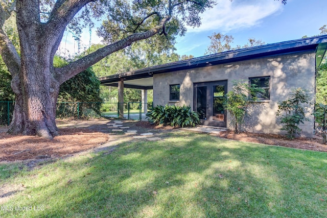 rear view of property with a yard, fence, and french doors