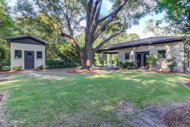 view of yard with french doors, a carport, an outdoor structure, and fence