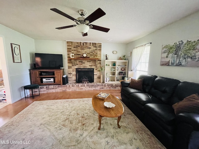 6324 Country Ln, Moss Point, MS 39562 - living room featuring wood finished floors, a ceiling fan, a fireplace, and a textured ceiling