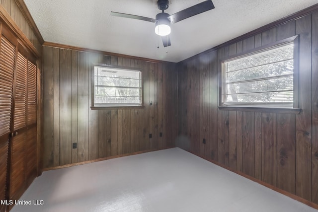2610 Demaret Dr, Gulfport, MS 39507 - unfurnished bedroom with a closet, wooden walls, a textured ceiling, a ceiling fan, and crown molding