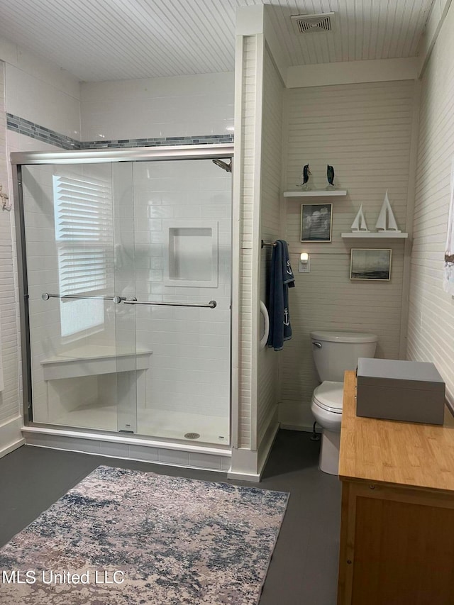 bathroom with vanity, concrete floors, toilet, and a shower with door