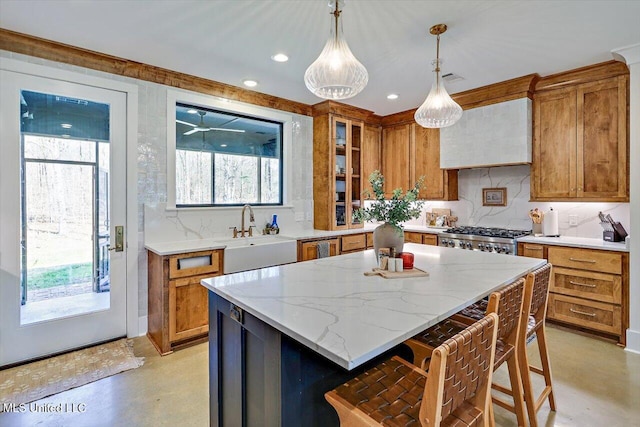 kitchen featuring brown cabinetry, a sink, range, and custom range hood