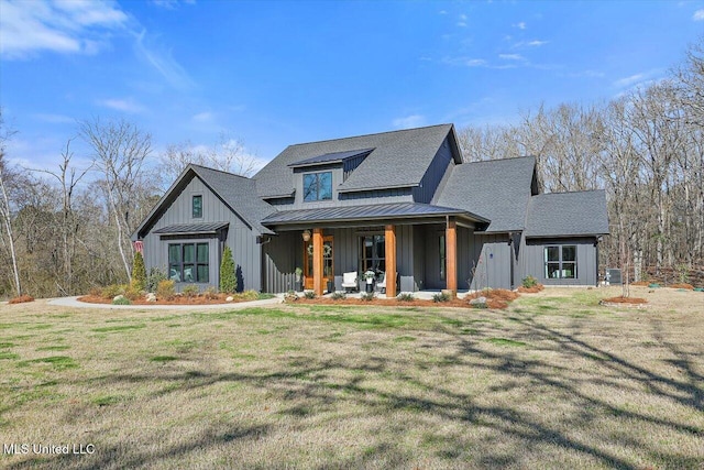 modern farmhouse featuring a shingled roof, covered porch, a front yard, a standing seam roof, and metal roof