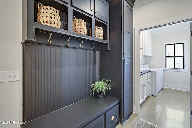 mudroom featuring concrete floors, baseboards, and separate washer and dryer