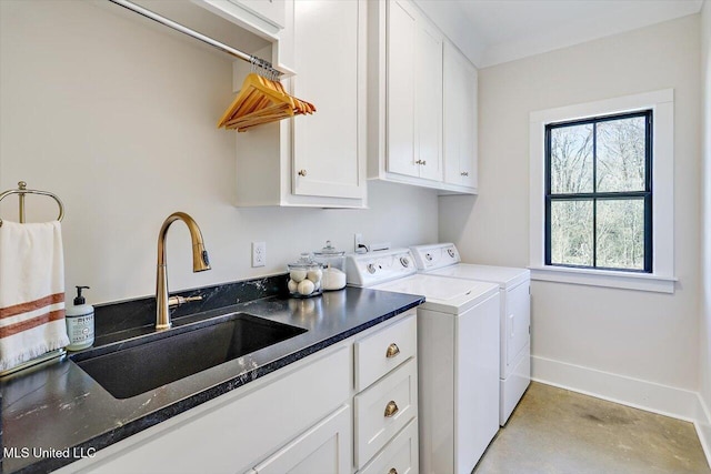 clothes washing area with washer and dryer, cabinet space, a sink, and baseboards