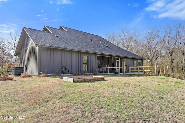 rear view of property with a shingled roof, a sunroom, cooling unit, a yard, and board and batten siding