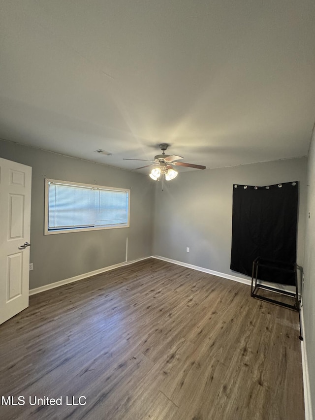 empty room with baseboards, wood finished floors, visible vents, and ceiling fan