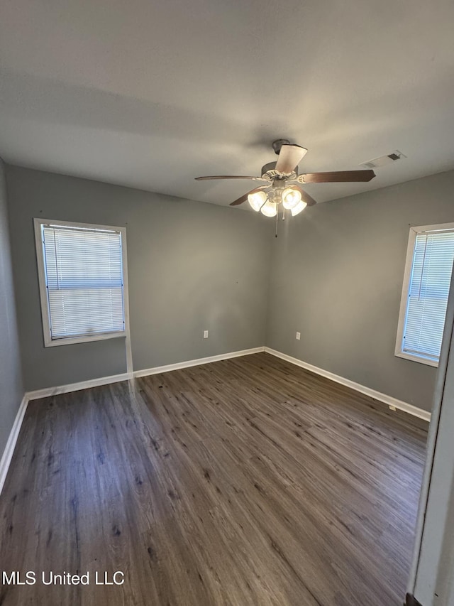 empty room featuring dark wood finished floors, visible vents, baseboards, and ceiling fan