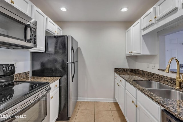 kitchen with sink, white cabinetry, light tile patterned floors, dark stone counters, and stainless steel appliances