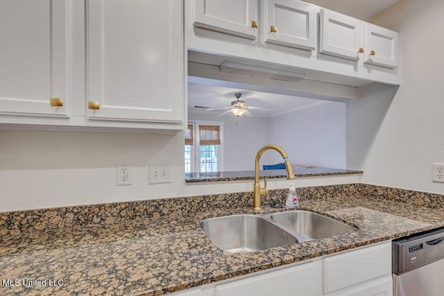 kitchen with sink, white cabinetry, dark stone countertops, stainless steel dishwasher, and ceiling fan