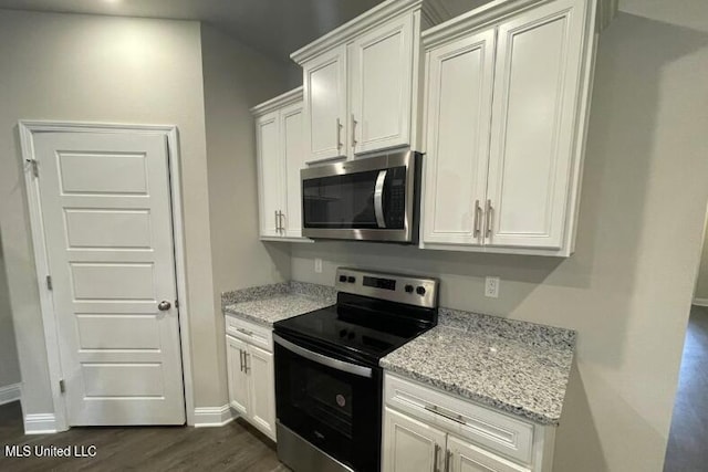 kitchen featuring dark wood finished floors, light stone countertops, white cabinetry, and appliances with stainless steel finishes