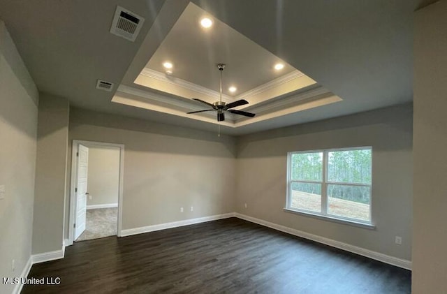 empty room featuring a tray ceiling, visible vents, and crown molding