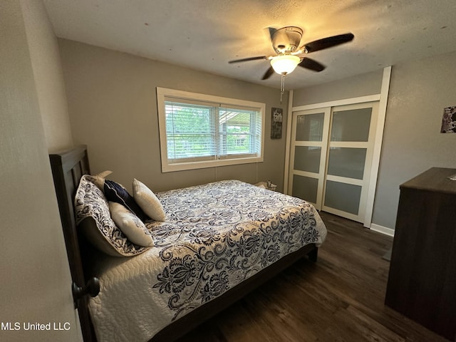 bedroom with ceiling fan, a closet, baseboards, and dark wood-type flooring