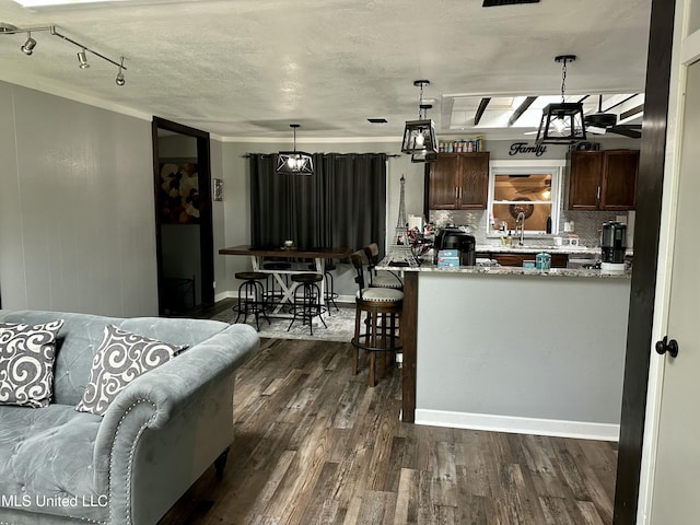 kitchen featuring a textured ceiling, tasteful backsplash, dark wood finished floors, and decorative light fixtures