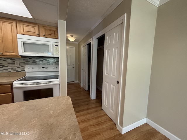 248 Lakeside Villa Unit J, Diamondhead, MS 39525 - kitchen featuring white appliances, decorative backsplash, light wood finished floors, baseboards, and crown molding